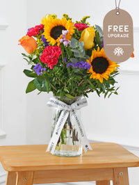 Colour Burst Vase Free Upgrade – Brighten up any room with our "Colour Burst" arrangement, featuring stunning sunflowers, cerise carnations,...