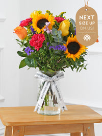Colour Burst Vase Next Size Up – On Us! – Brighten up any room with our "Colour Burst" arrangement, featuring stunning sunflowers, cerise carnations,...