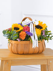 Colour Burst Basket –  Brighten up any room with our "Colour Burst" arrangement, featuring stunning sunflowers, cerise carnations,...