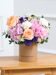 Sweet Pastel Hatbox –  Brighten up any space with our 'Sweet Pastel' arrangement, featuring soft pink hydrangeas, peach...