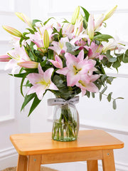 Pink Lily - Vase – The Pink Lily in a vase adorned with vibrant eucalyptus and pistach leaves serves...