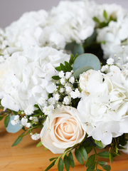 Pure Bliss Wreath – This enchanting funeral wreath, embellished with pristine white hydrangeas, roses, carnations, gypsophila, and accented...