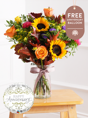 Anniversary Autumn Charm - Vase with Free Anniversary Balloon – Brighten up any room with our "Autumn Charm" arrangement, featuring stunning sunflowers, cerise carnations,...