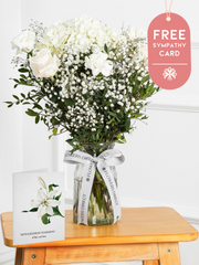 Sympathy Pure Bliss - Vase with Free Sympathy Card – An exquisite arrangement of white roses, carnations, and hydrangeas, delicately adorned with gypsophila, pistachio...