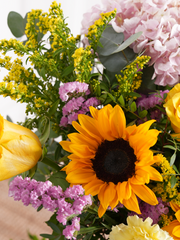 Sweet Meadow Vase – Bursting with the hues of summer, featuring sunflowers, yellow roses, solidago, pink statice, pink...